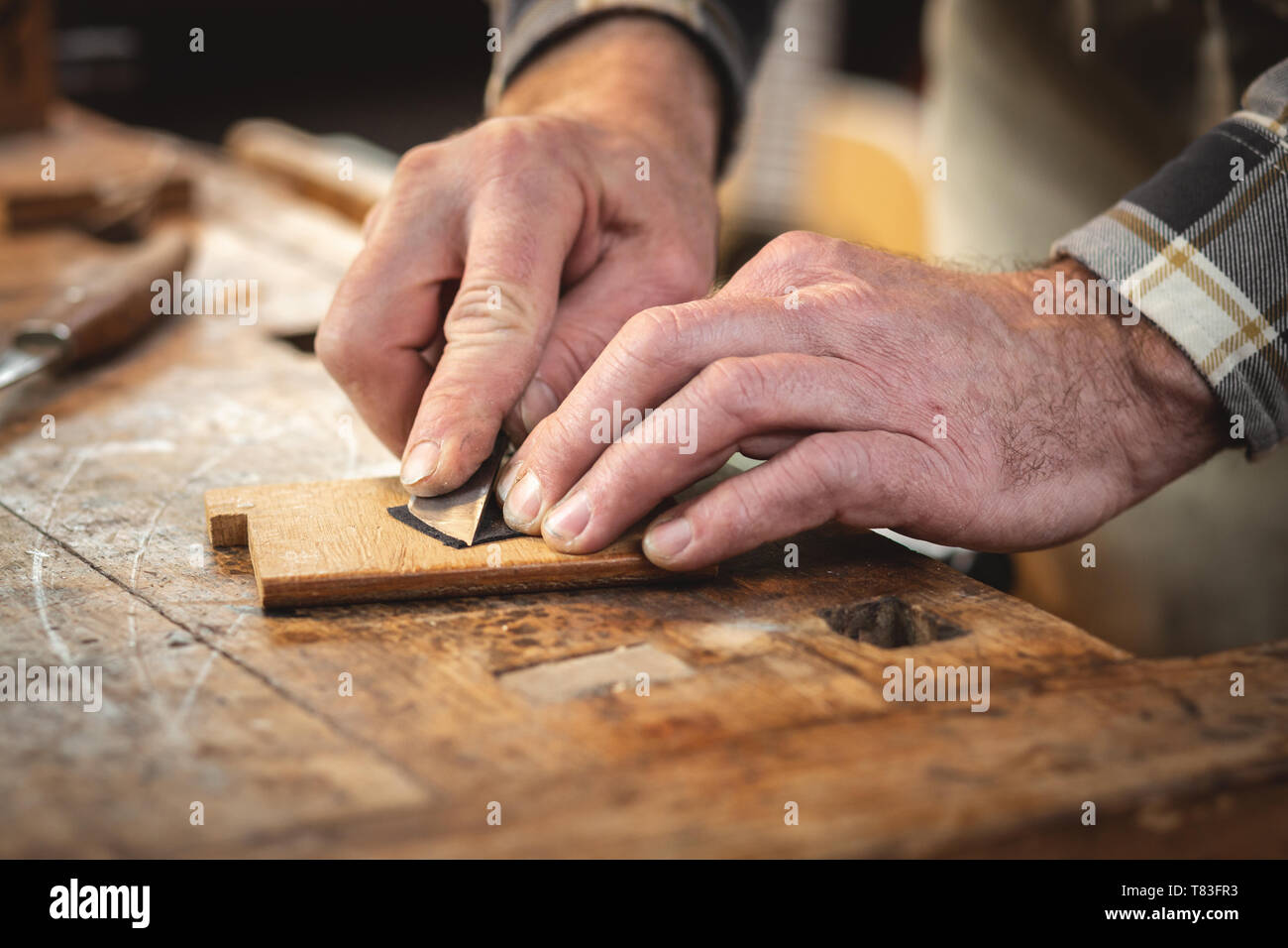 Die Hände eines Handwerkers schneiden ein kleines Stück Leder Stockfoto