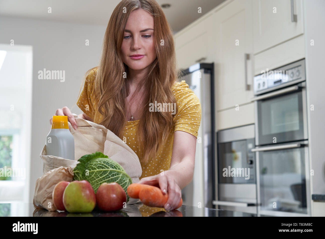 Frau Heimweg von Shopping Trip Auspacken Kunststoff Kostenlose Einkaufstaschen Stockfoto