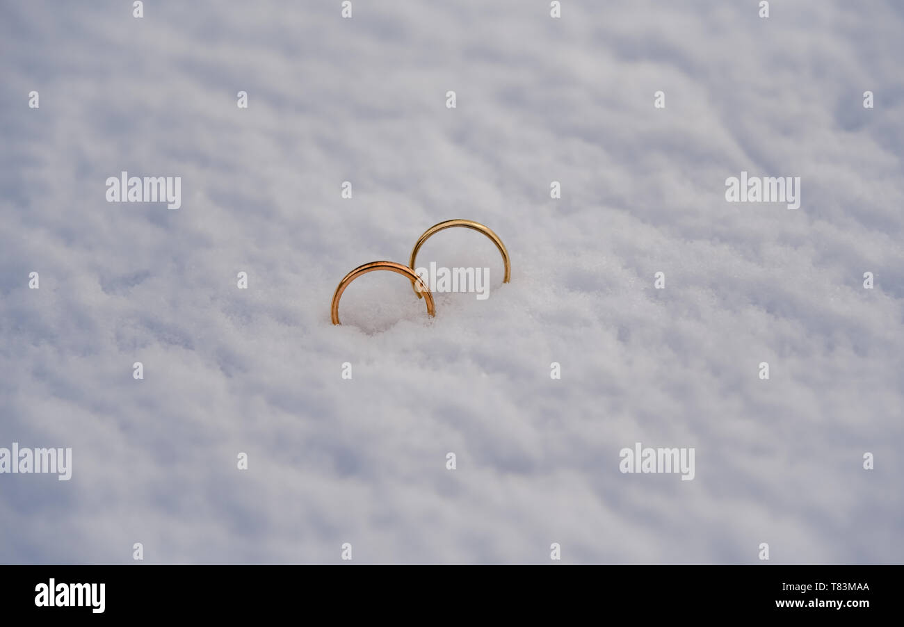 Zwei goldene Hochzeit Ringe in den frischen Schnee gelegt. Stockfoto