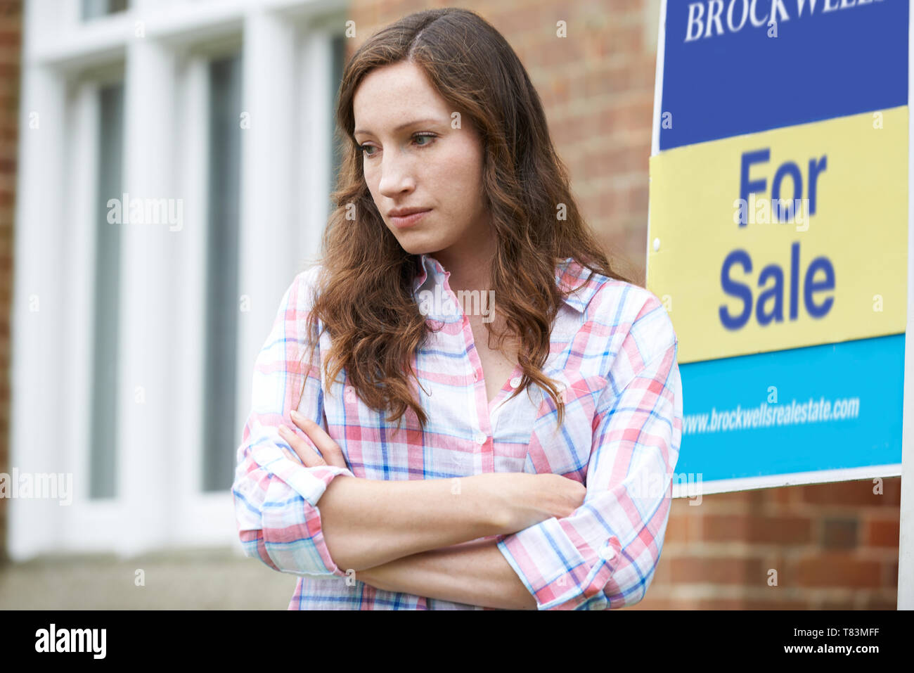 Junge Frau gezwungen nach Hause durch finanzielle Probleme stehen im Freien Neben Zu Verkaufen - Schild zu Verkaufen Stockfoto