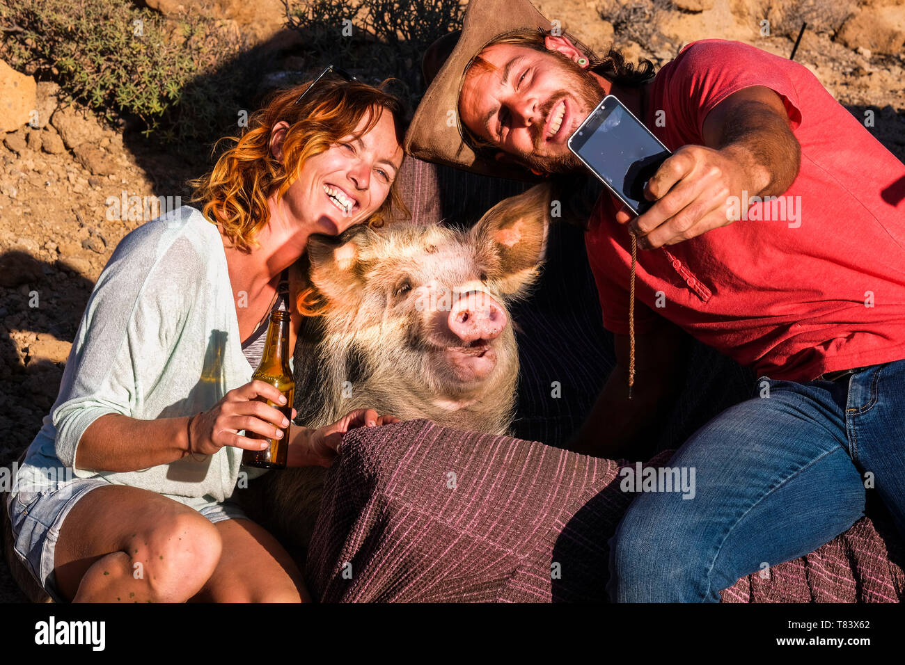 Gerne alternativen Charakter Tierliebhaber paar fröhliche Menschen genießen und Spaß haben, selfie Bild mit einem lustigen Schwein in Freundschaft - Verschiedene li Stockfoto