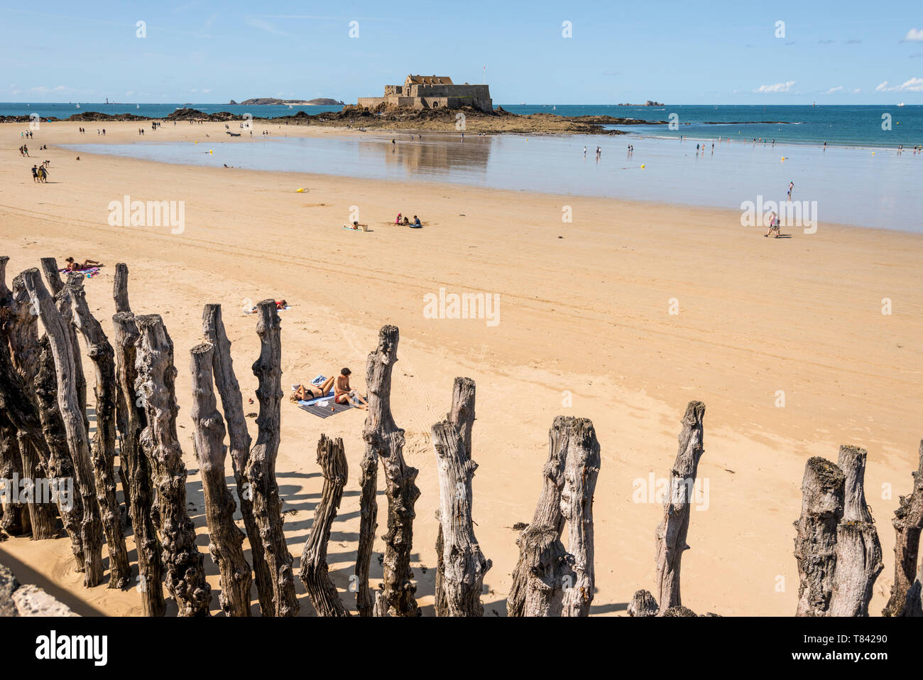 Menschen auf Sandstrand und Blick auf das Meer mit Fort National im Hintergrund, Bretagne, Frankreich Stockfoto