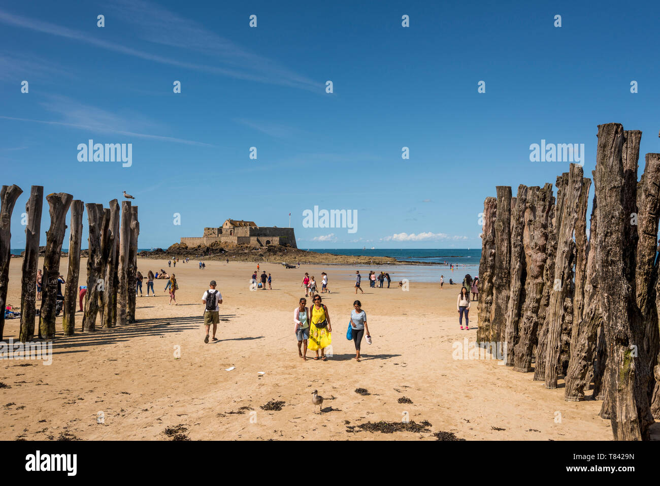 Menschen auf Sandstrand und Blick auf das Meer mit Fort National im Hintergrund, Bretagne, Frankreich Stockfoto