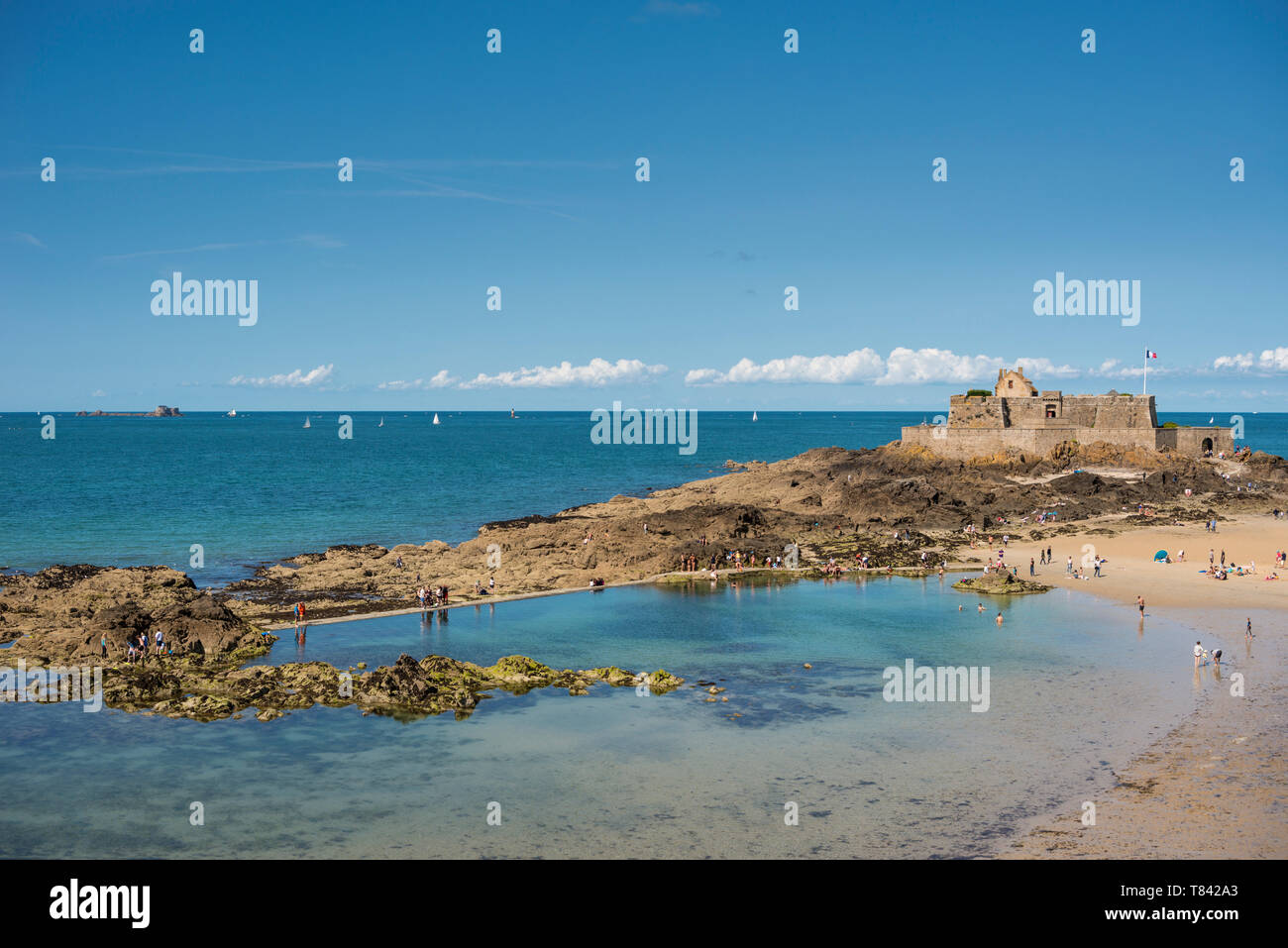 Menschen auf Sandstrand und Blick auf das Meer mit Fort National im Hintergrund, Bretagne, Frankreich Stockfoto