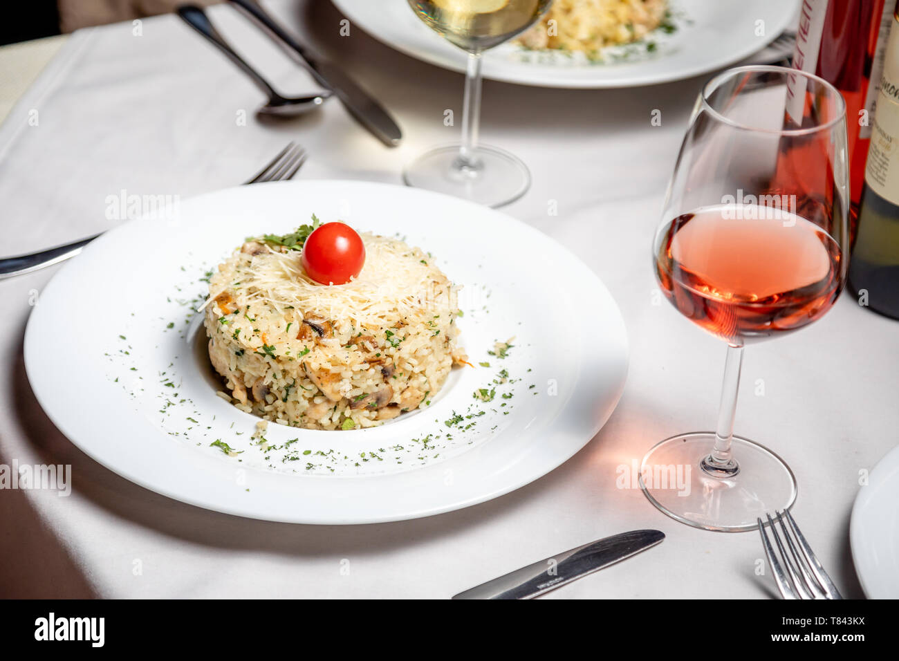 Risotto mit weißem Glas Wein am Tisch im Restaurant serviert. Stockfoto