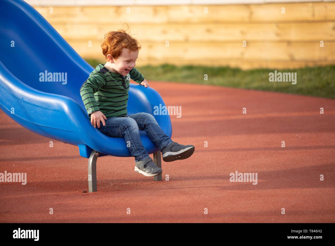 Junge spielt auf Folie in Spielplatz Stockfoto