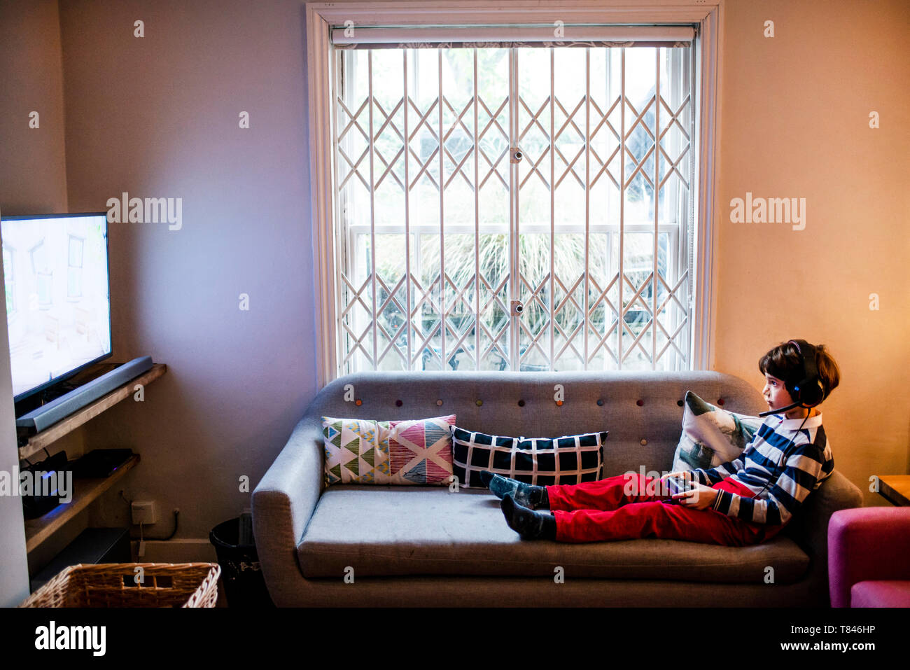 Junge saß auf dem Sofa spielen video spiel mit Game Controller Stockfoto