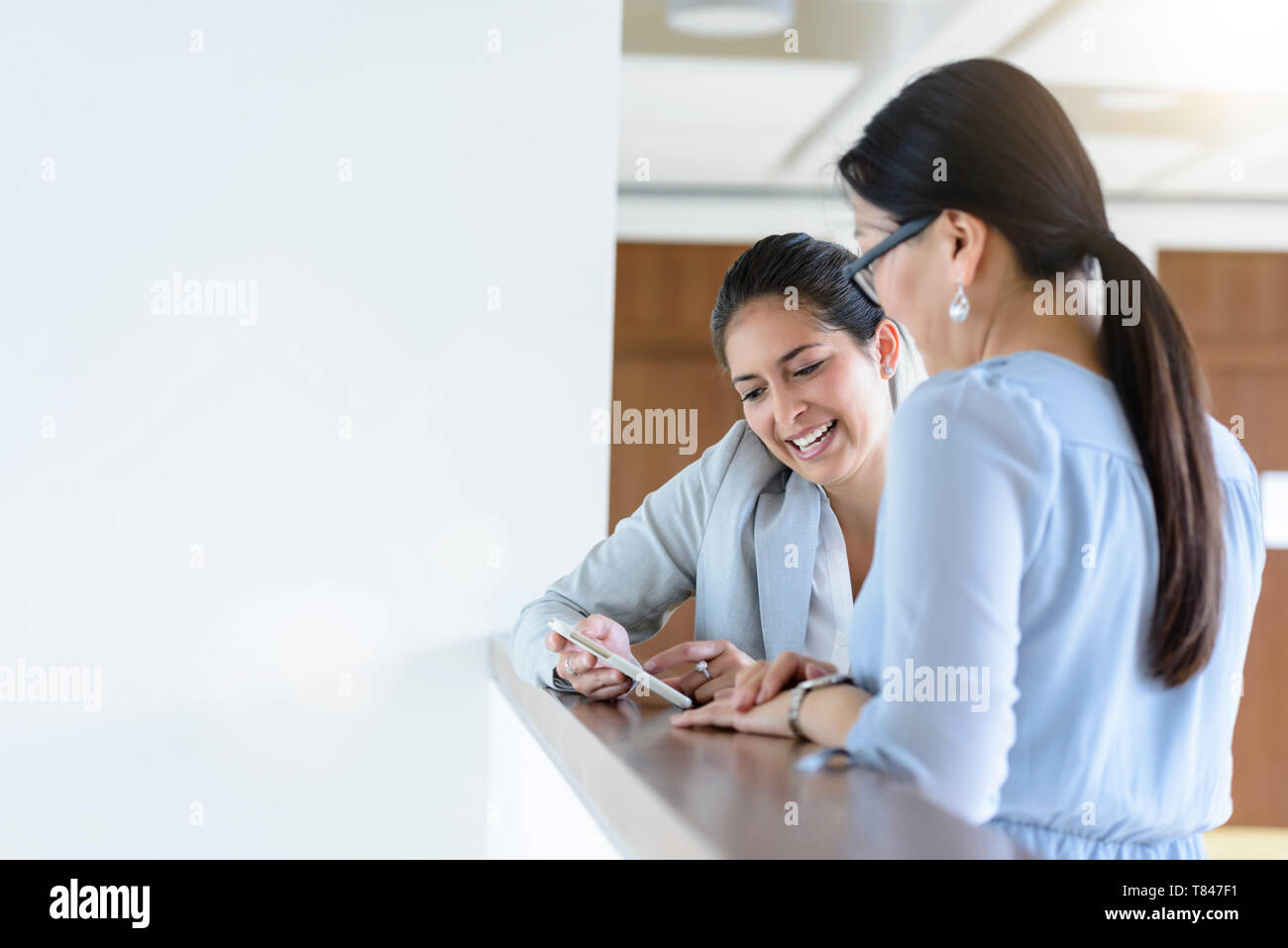 Unternehmerinnen sprechen und sie ihr Smartphone im Büro Stockfoto