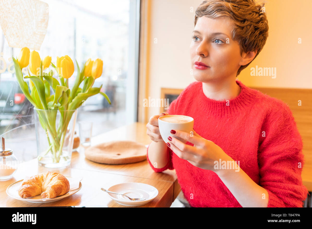 Mitte der erwachsenen Frau mit kurzen blonden Haaren Blick durch Fenster Cafe Stockfoto