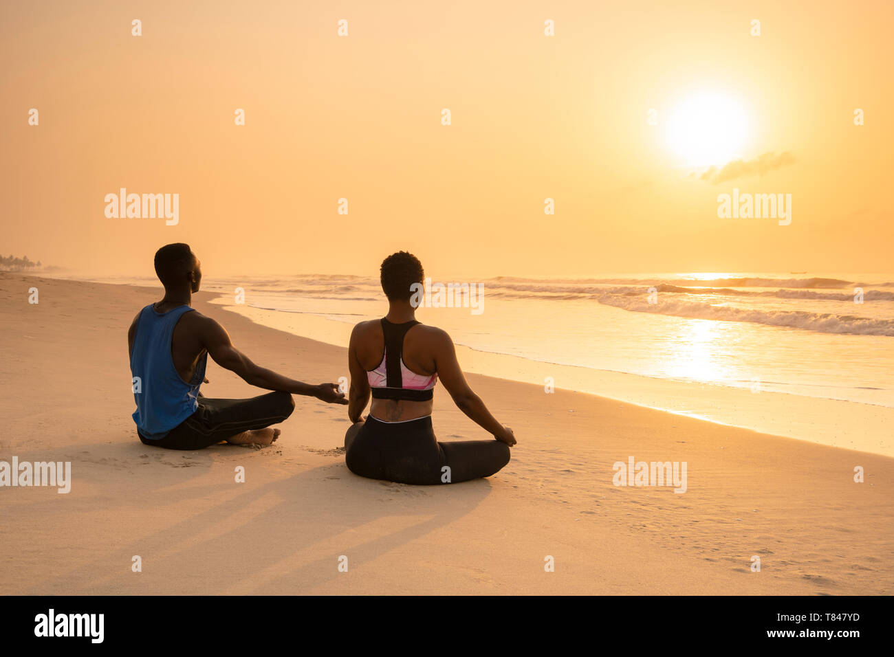 Paar Üben Yoga am Strand. Stockfoto