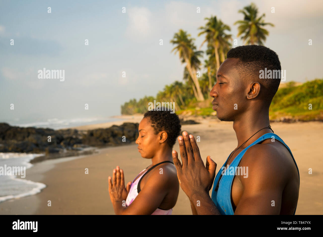 Paar Üben Yoga am Strand. Stockfoto