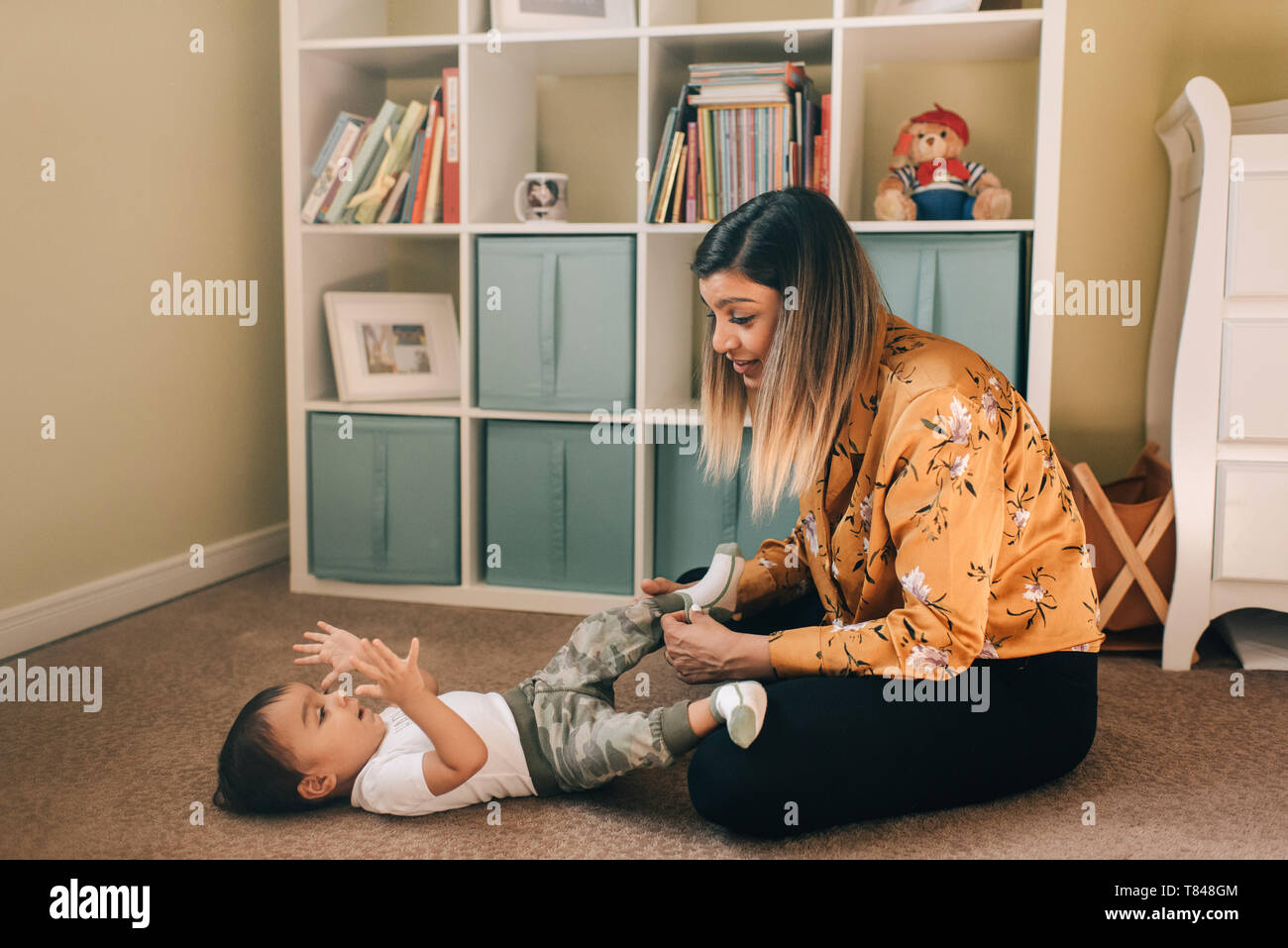 Mutter sitzt auf Kindergarten stock Socken auf Baby Sohn Stockfoto