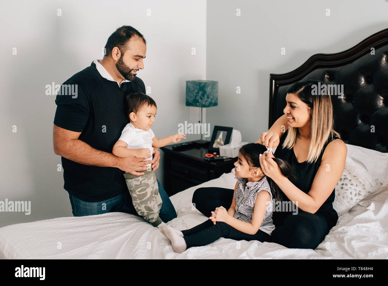 Baby auf Bett mit Vater, Mutter und die Schwester Haar Stockfoto