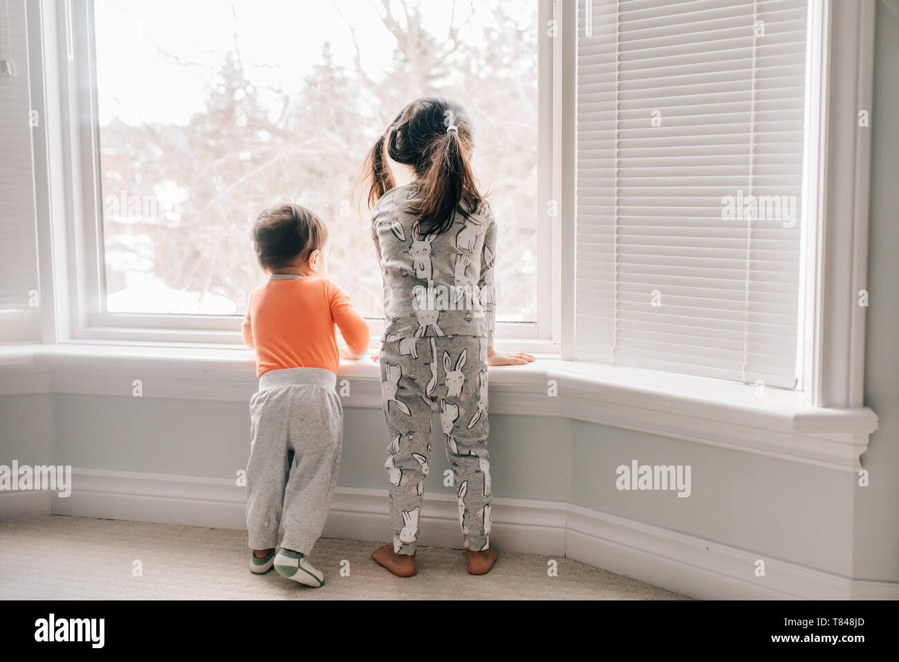 Mädchen und Bruder durch Wohnzimmer Fenster suchen, Ansicht von hinten Stockfoto