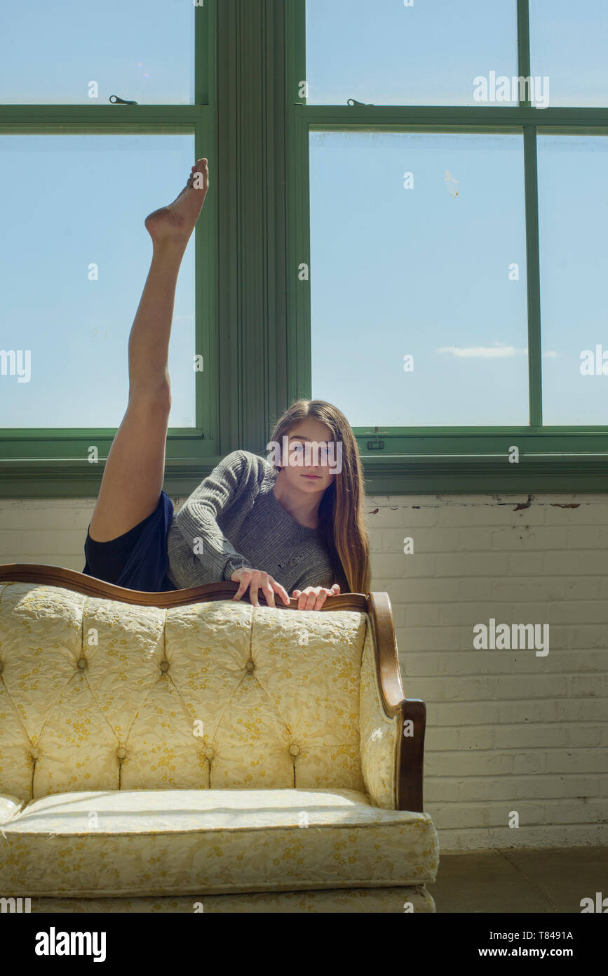 Junges Mädchen im Tanz Studio hinter Sofa mit Bein angehoben, Porträt Stockfoto