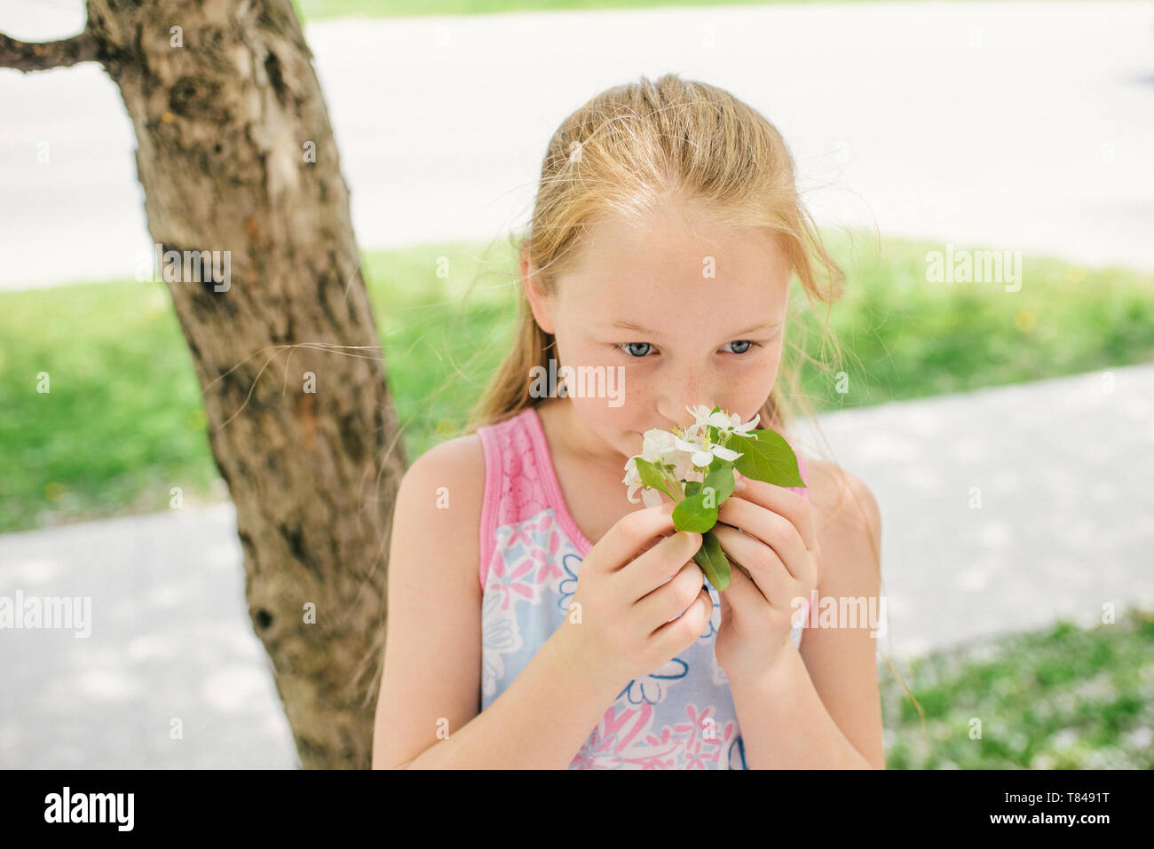 Mädchen riechende Blume auf vorstadtstraße Stockfoto