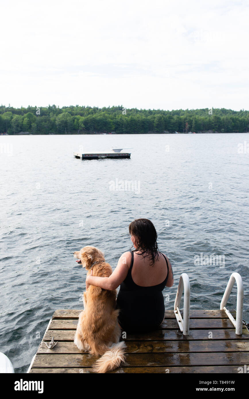 Frau mit Hund sucht vom See pier, Rückansicht, Kingston, Ontario, Kanada Stockfoto