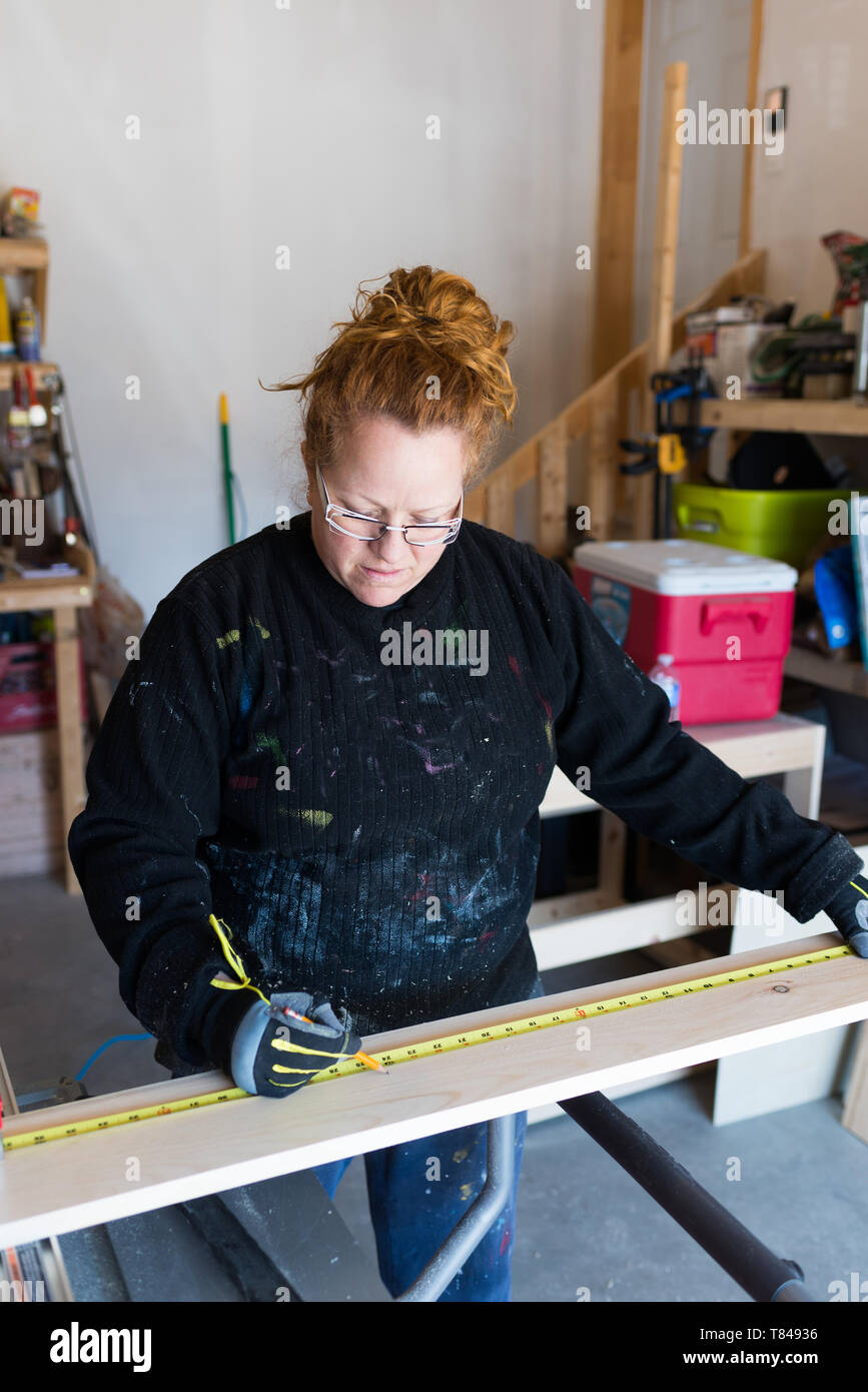 Reife weibliche Tischler messen Holzplanken in Werkstatt Stockfoto