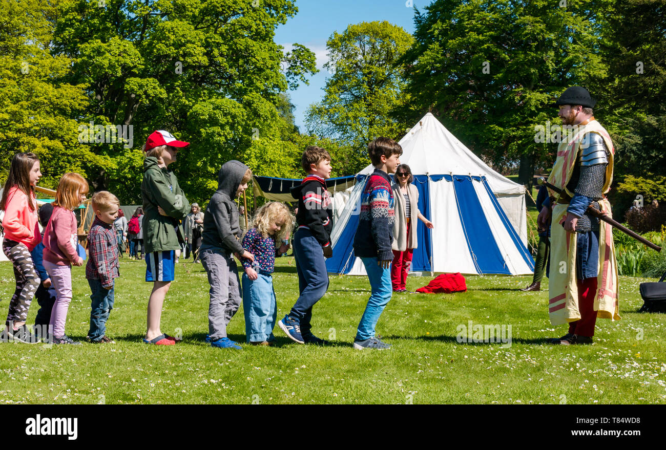 Dirleton Castle, East Lothian, Schottland, Vereinigtes Königreich, 11. Mai 2019. Tag des Mittelalters: historische Umgebung Schottland Familientag am lebendigen mittelalterlichen Dorf in den Schlossgarten. Kinder haben Spaß beim Lernen in einer Armee bis März Stockfoto