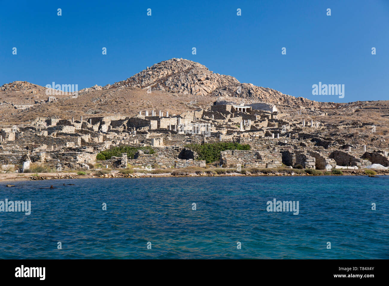 Delos, Mykonos, südliche Ägäis, Griechenland. Blick vom Meer auf die Delos archäologische Stätte an den unteren Hängen des Berg Kynthos. Stockfoto
