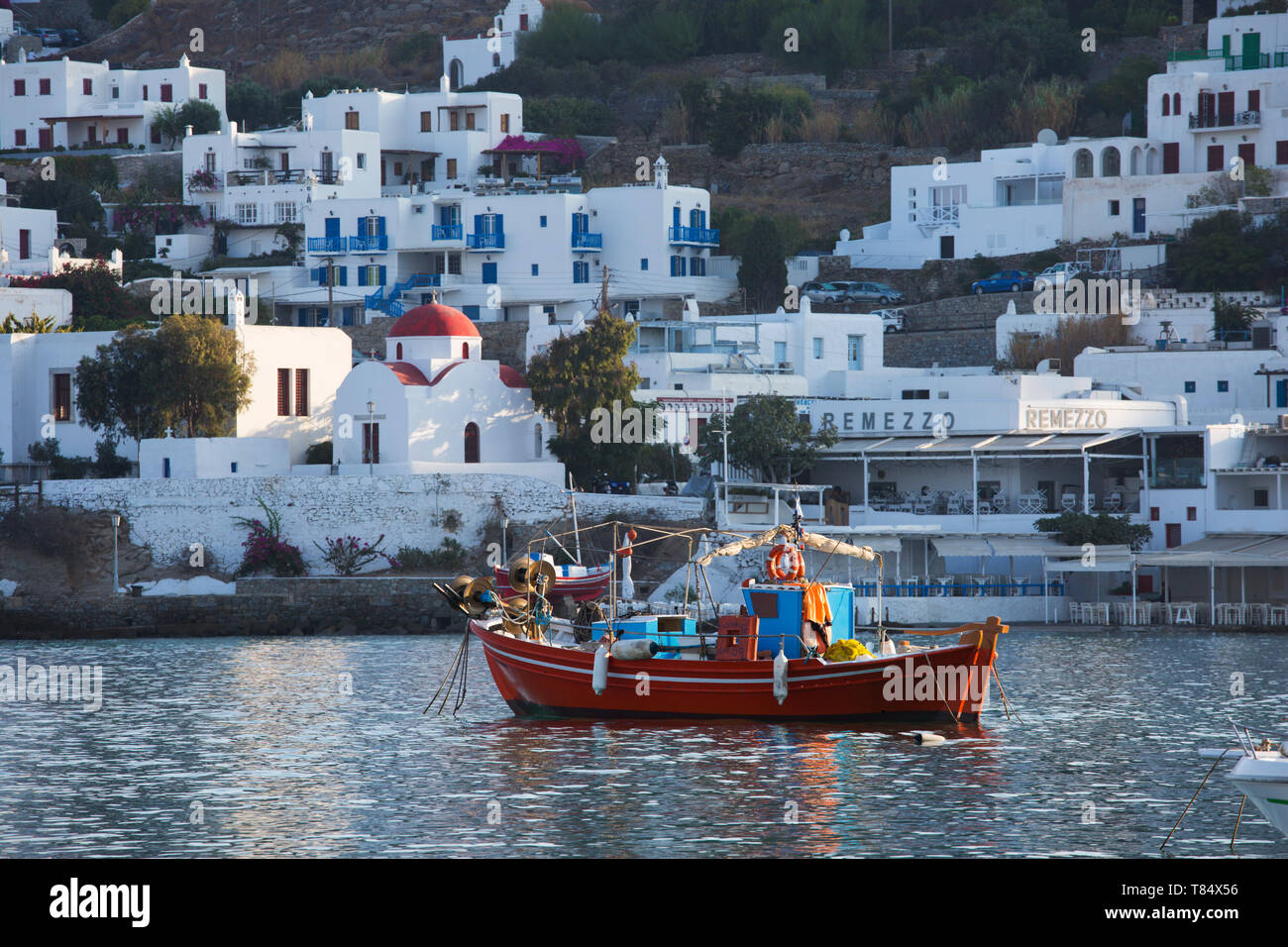 Mykonos Stadt, Mykonos, südliche Ägäis, Griechenland. Bunte Fischerboote im Hafen, rot-gewölbte Kirche im Hintergrund. Stockfoto