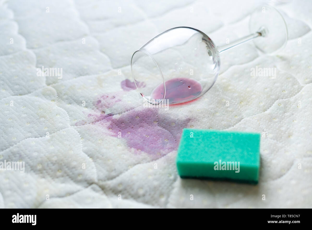 Reinigung Wein mit Schwamm Fleck. Verschüttete Wein auf weißen Bettlaken. Fallengelassen Wineglass. Pech, unglückliche Situation. Stockfoto