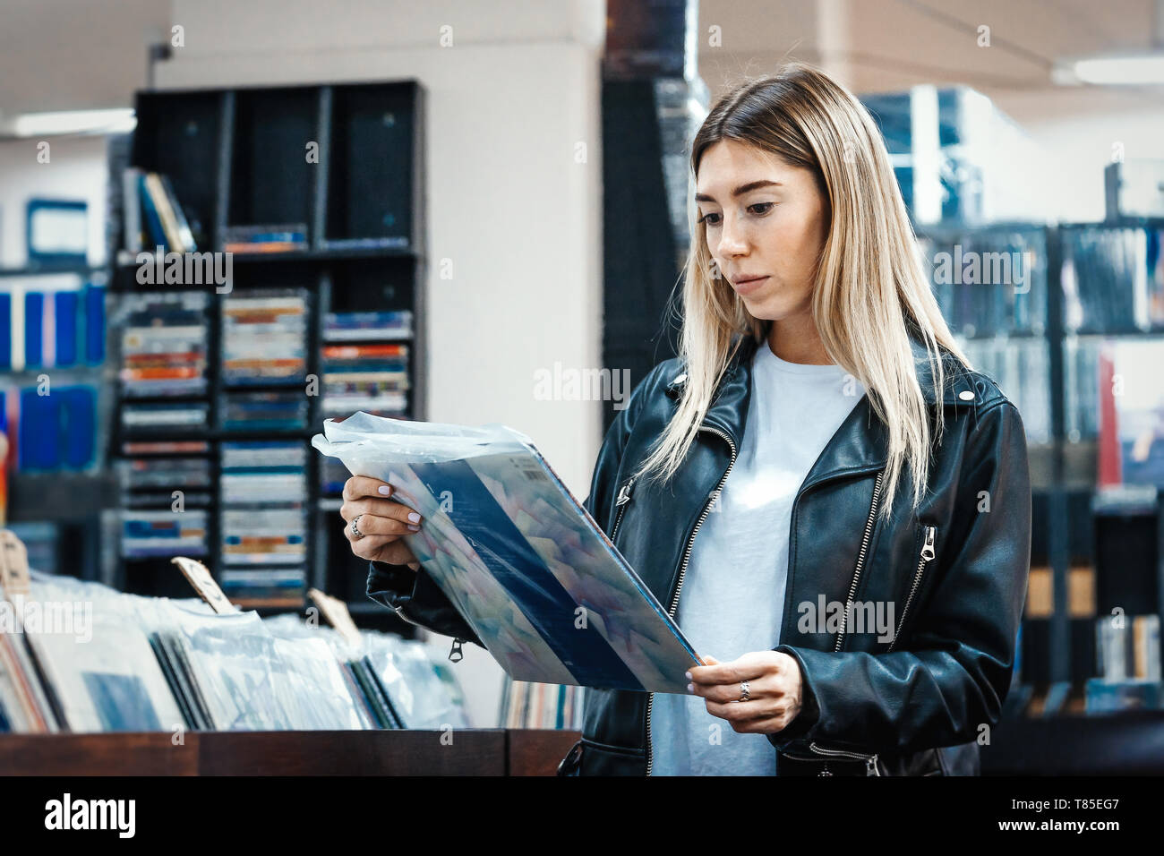 Junge attraktive Frau Wahl Schallplatte in der Musik Record Shop. Melomaniac oder Musik süchtiger Konzept. Stockfoto