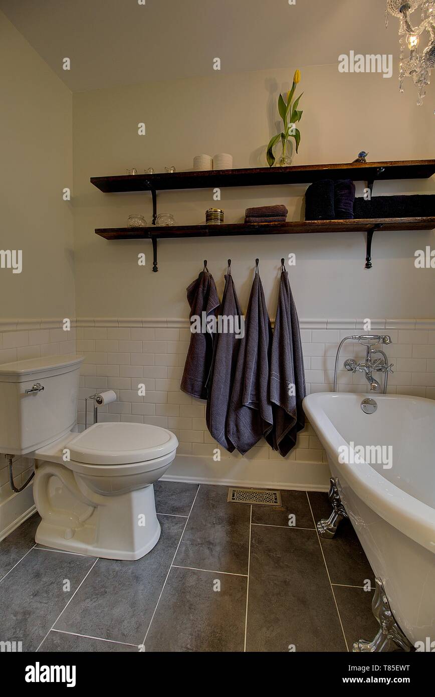 Aktualisiert Badezimmer mit Fliesen im Subway-Stil, frei stehender Badewanne, vintage Holz Regale. Moderne Wohnkultur. Stockfoto