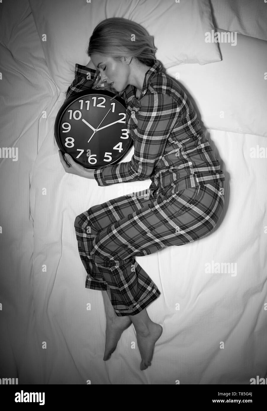 Frau schlafen im Bett mit Uhr Stockfoto