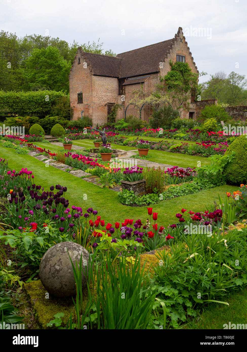 Chenies Manor versunkenen Garten mit Pavillon und Teich Anfang Mai zeigen bunte Tulpen, Skulptur und frische grüne Blätter wunderschön gestaltet. Stockfoto