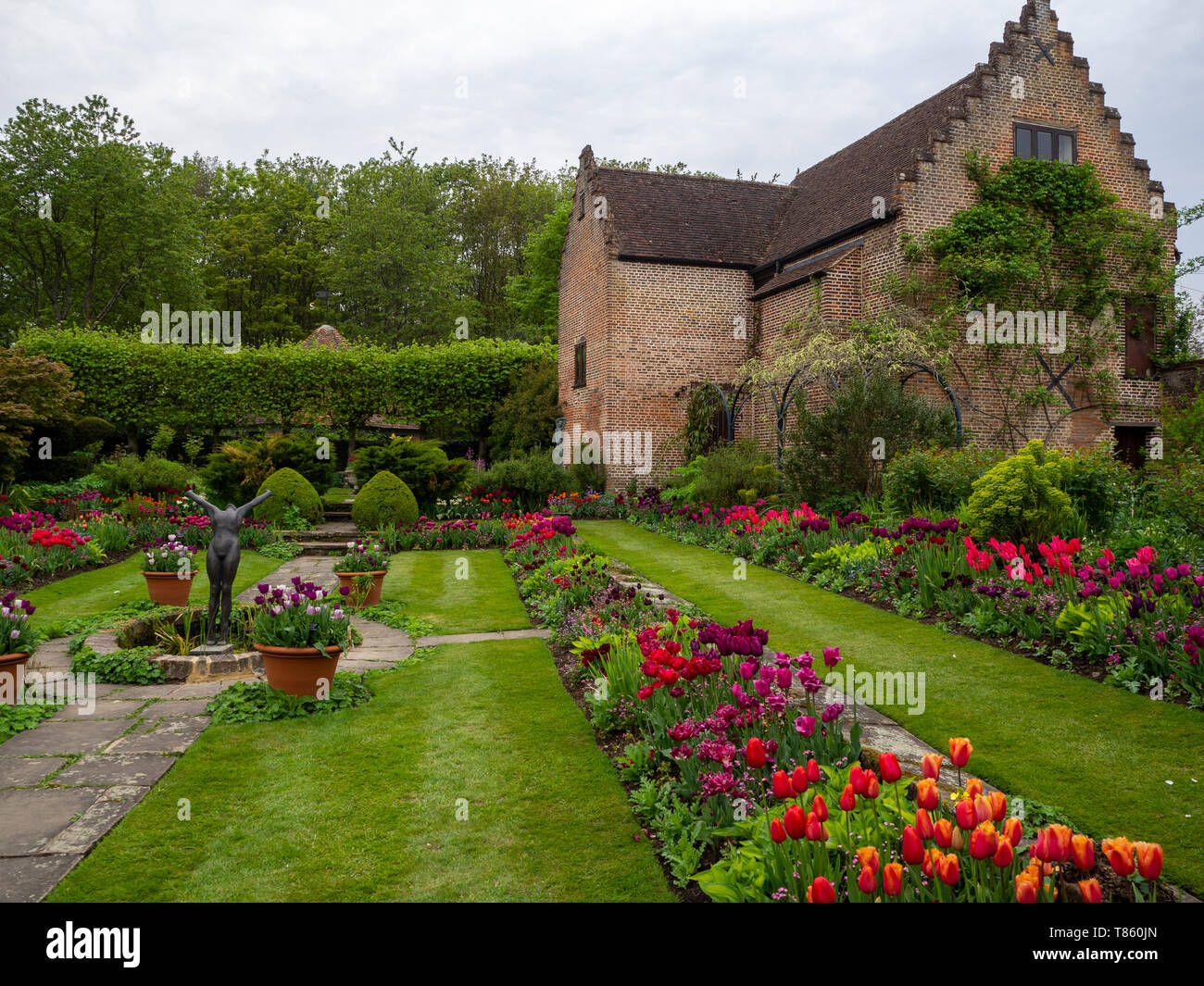 Chenies Manor versunkenen Garten mit Pavillon und Teich Anfang Mai zeigen bunte Tulpen, Skulptur und frische grüne Blätter wunderschön gestaltet. Stockfoto
