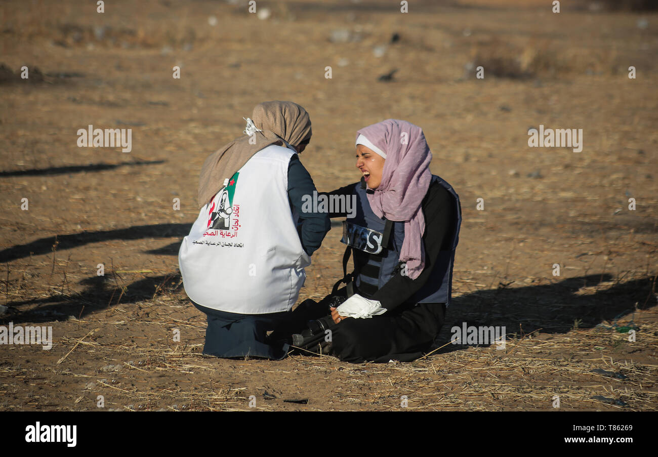 Eine palästinensische Sanitäter gesehen helfen ein Journalist erstickt von Tränengas während der Auseinandersetzungen. Palästinenser stießen mit israelischen Truppen während einer Demonstration, in der Sie für die Aufhebung der israelischen Belagerung von Gaza und anspruchsvolle das rechte Haus am Grenzzaun zwischen Israel und Gaza im südlichen Gazastreifen Rückkehr aufgerufen. Stockfoto