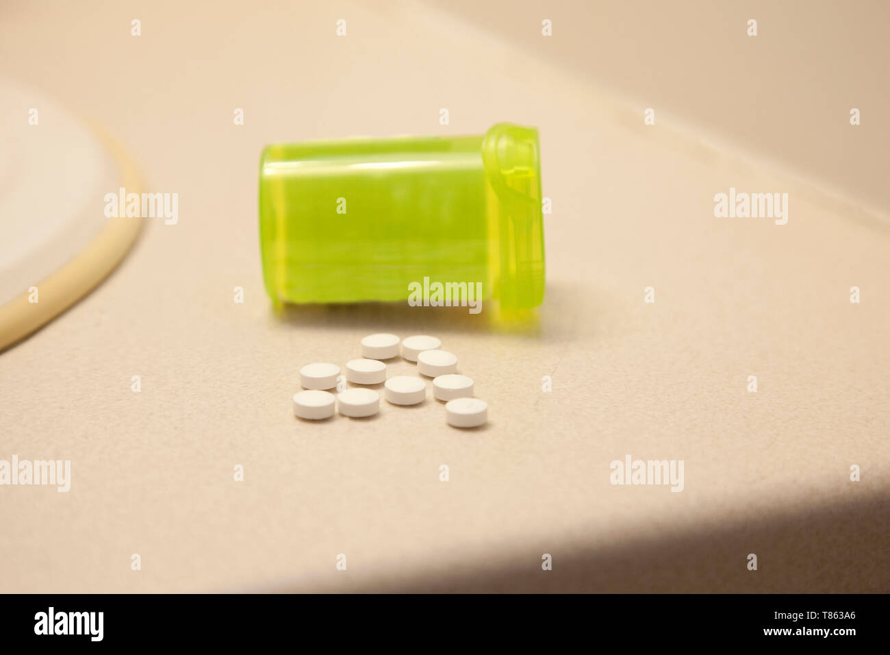 Eine grüne Pille Durchstechflasche mit weißem Medikation auf das Badezimmer zu Hause verschüttet Stockfoto