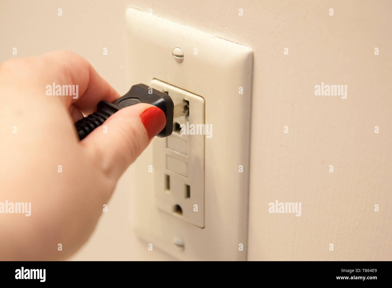 Hand Einstecken oder Abziehen ein Netzkabel an eine Steckdose anschließen Stockfoto