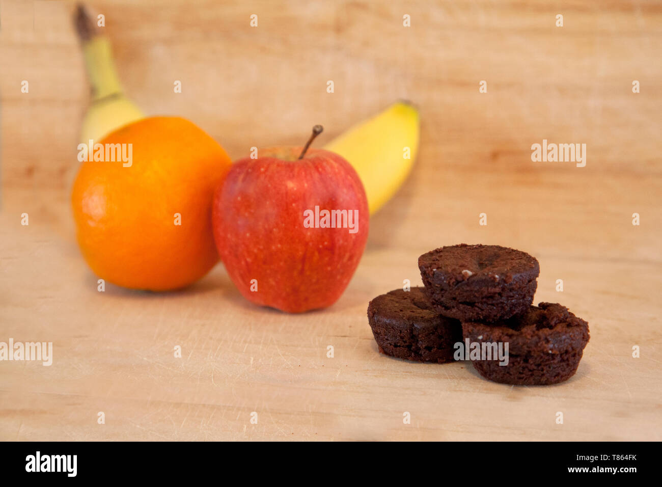 Ein kleiner Haufen von Brownies neben einem Apfel, Banane und Orange machen verschiedene Dessert Auswahl Stockfoto