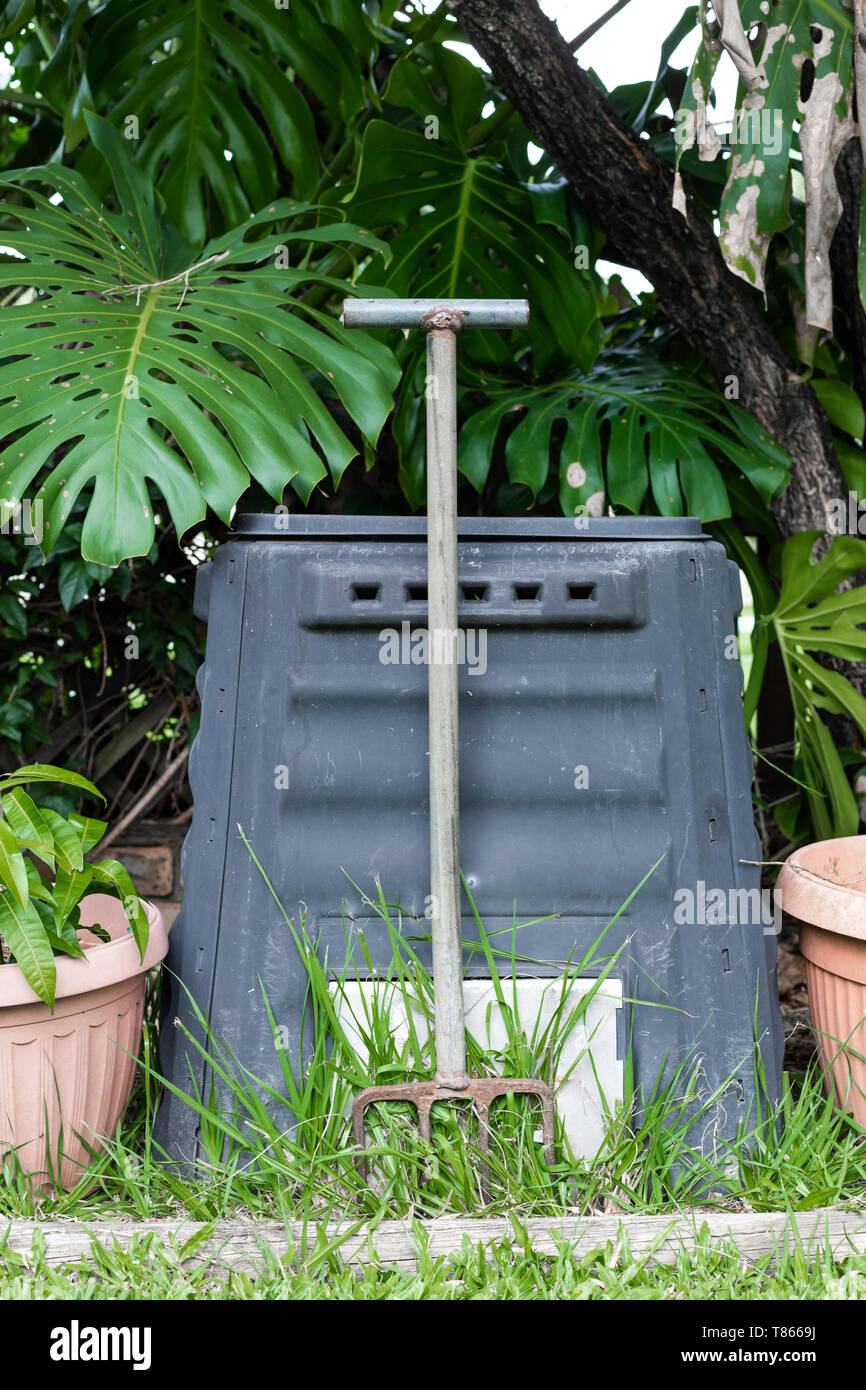 Eine Komposttonne und Pitch Gabel in einer australischen Garten im Hinterhof, die von Pflanzen und grünes Gras umgeben Stockfoto