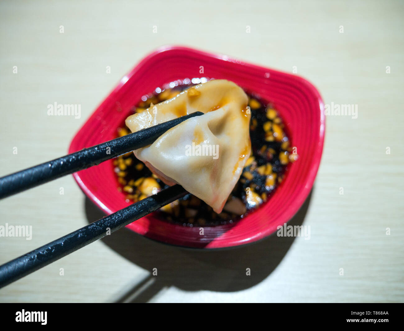 Chinesische Knödel in Stäbchen eingetaucht in Soja Knoblauch Sauce Stockfoto