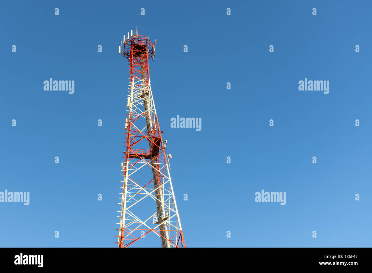 Eine rot-weiße Mobiltelefon Telekommunikation Turm auf einem blauen Himmel Hintergrund suchen. Stockfoto