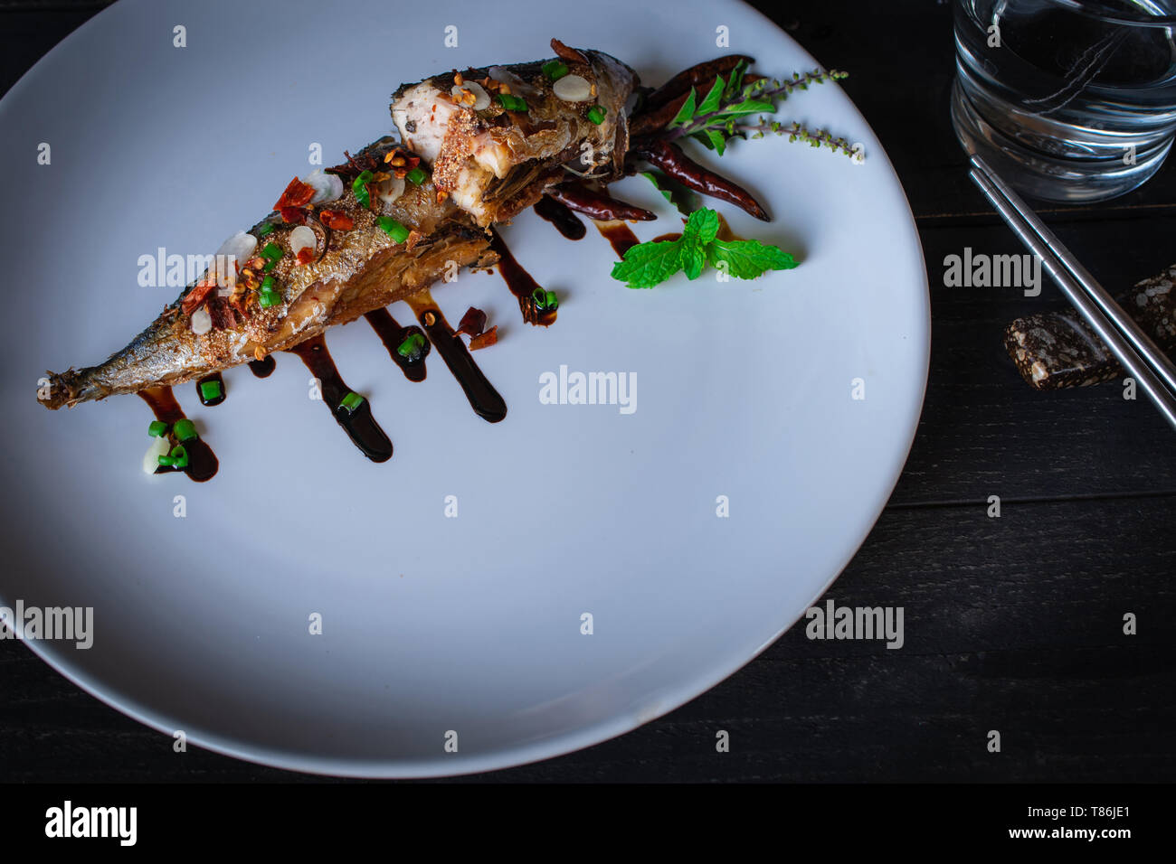 Saba gebratener Fisch mit Sauce auf weiße Platte und Dekoration von ...