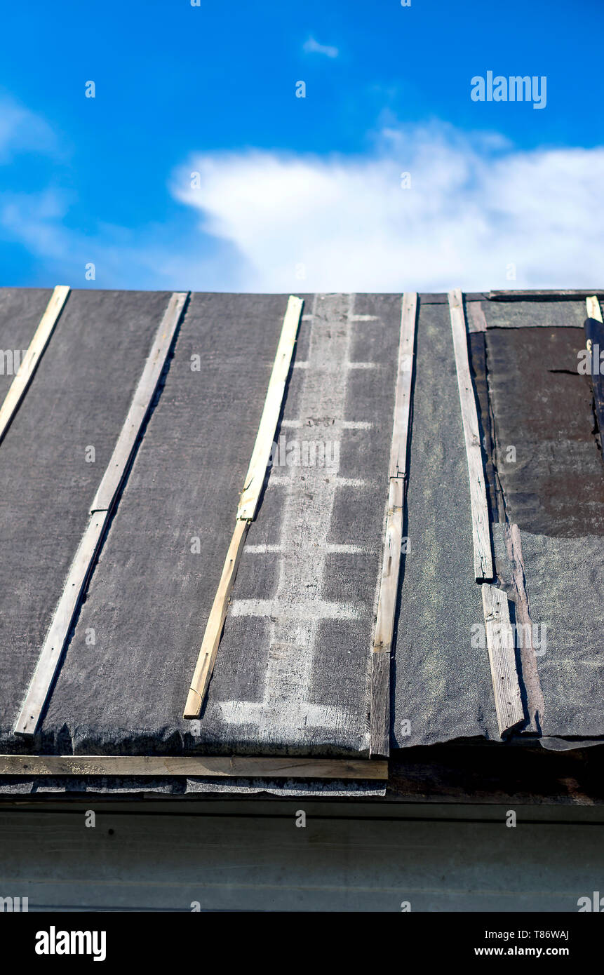 Trace von einer Leiter auf eine Scheune Dach mit Abdichtung Teerpappe gegen Sommer Blauer Himmel und weiße Wolken. Dacharbeiten Reparaturen, Bau Konzept Stockfoto