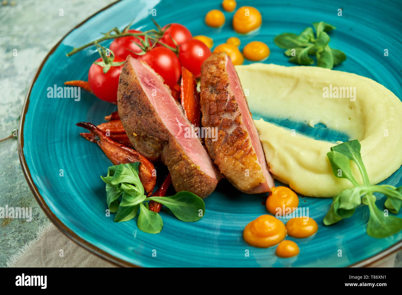 Gebratenes Fleisch mit geschredderten Kartoffeln und Tomaten auf eine schöne Platte auf grauem Hintergrund Stockfoto