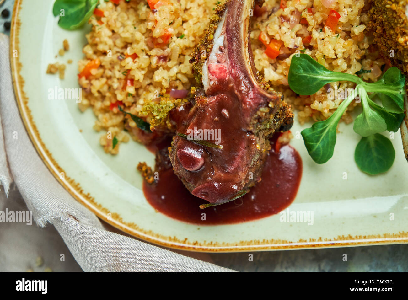 Gegrillte Lammkoteletts und Risotto auf eine schöne Platte auf grauem Hintergrund Stockfoto