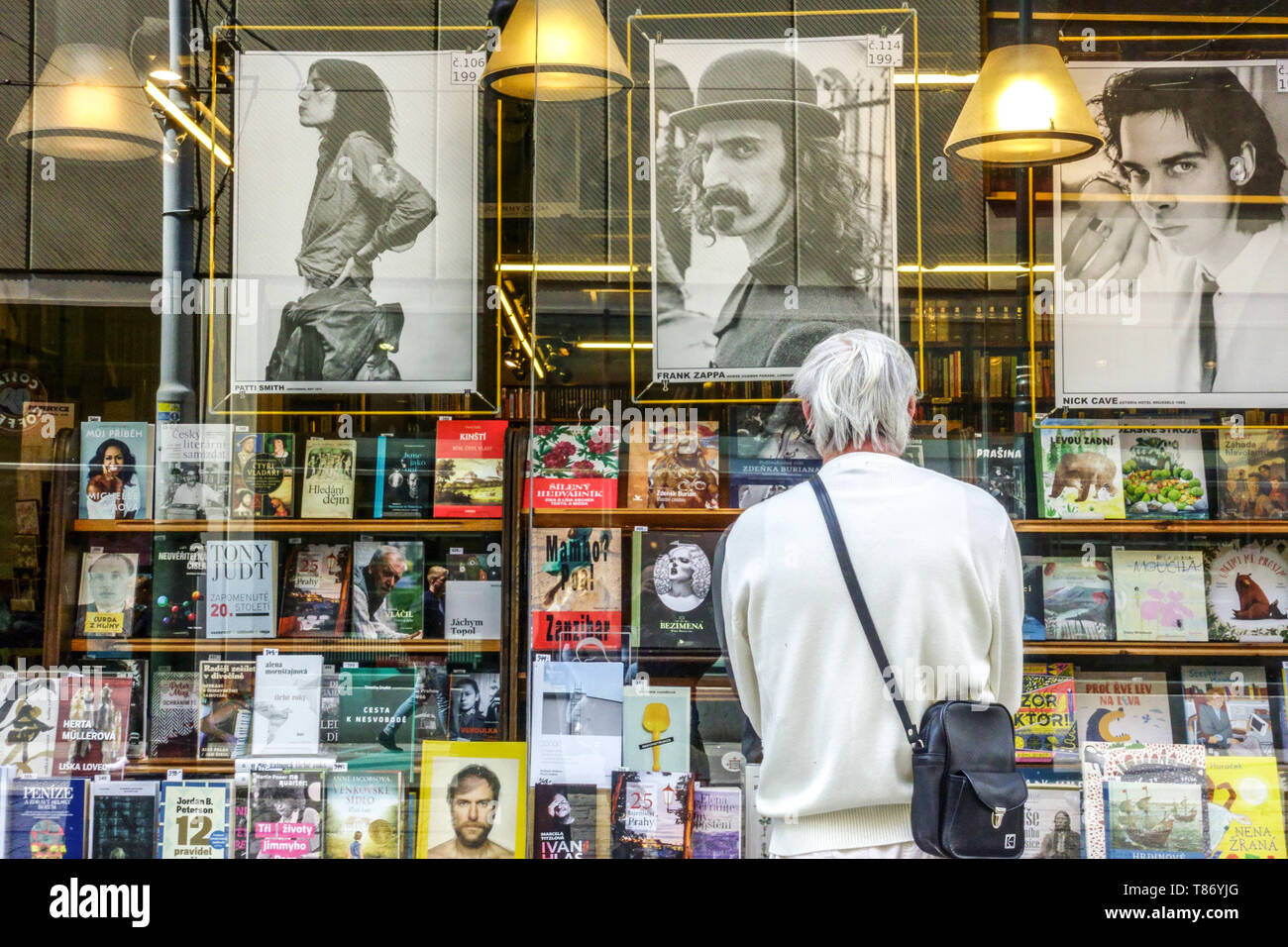 Prager Plakate in Buchhandlung Tschechische Republik. Der Mann sieht sich Poster und Bücher im Schaufenster der Prager Buchhandlung Spalena Street an Stockfoto