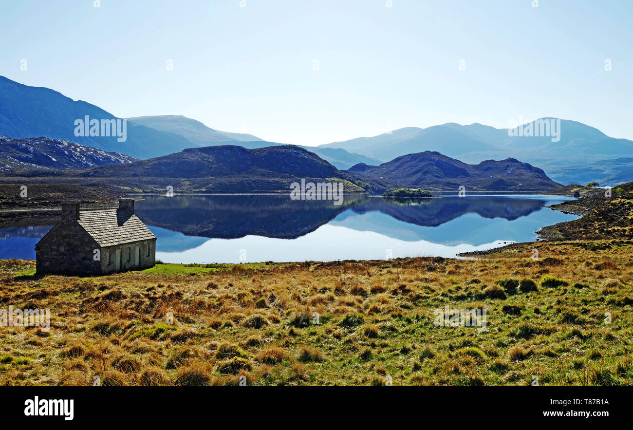 Alte Hütte am Loch Stack, Sutherland, Schottisches Hochland, Großbritannien, schönen, ruhigen friedlichen Frühlingsmorgen, Berge in ruhiger See wider. Stockfoto