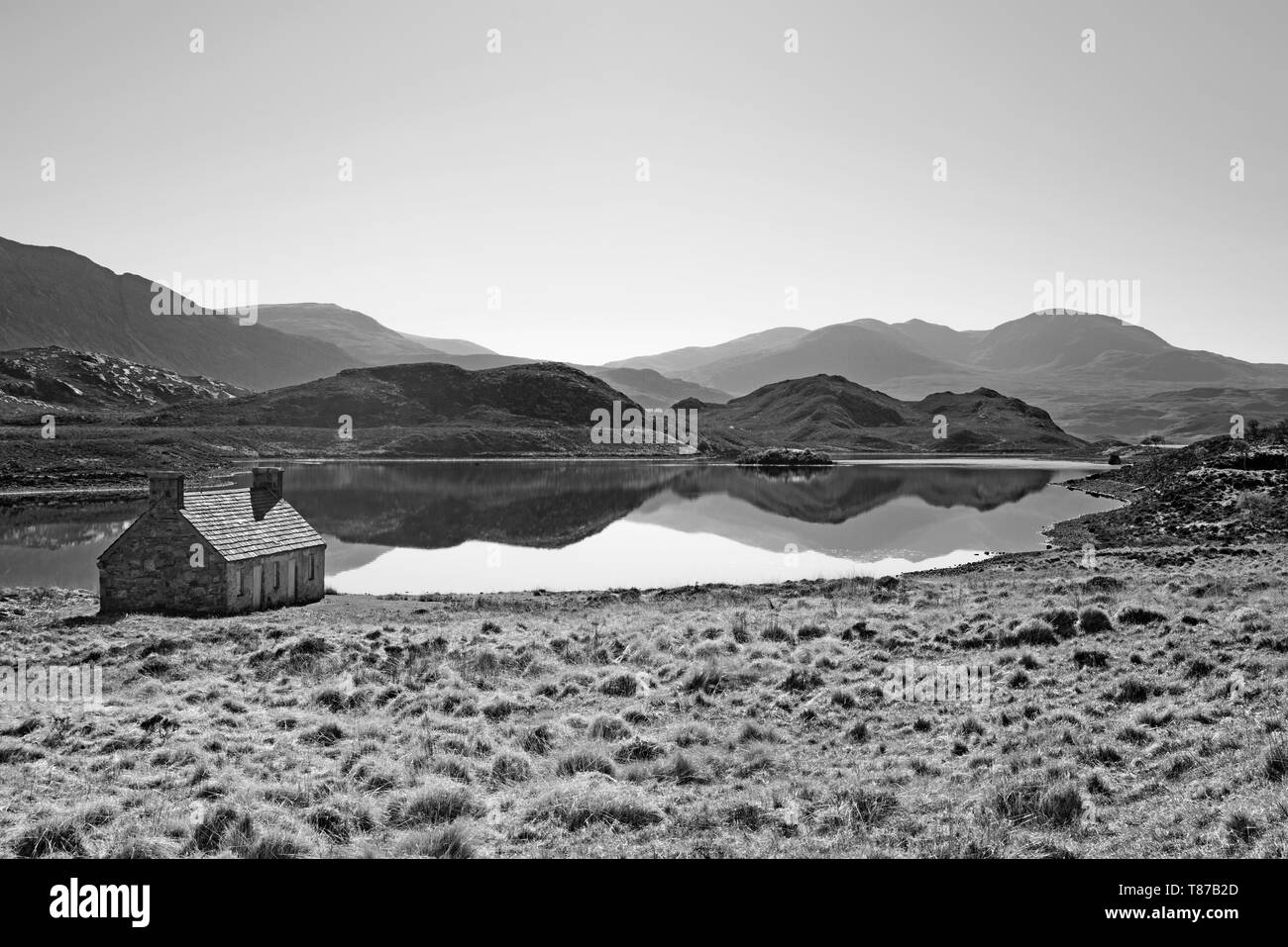 Alte Hütte am Loch Stack, Sutherland, Schottisches Hochland, Großbritannien, schönen, ruhigen friedlichen Frühlingsmorgen, Berge in ruhiger See wider. Stockfoto