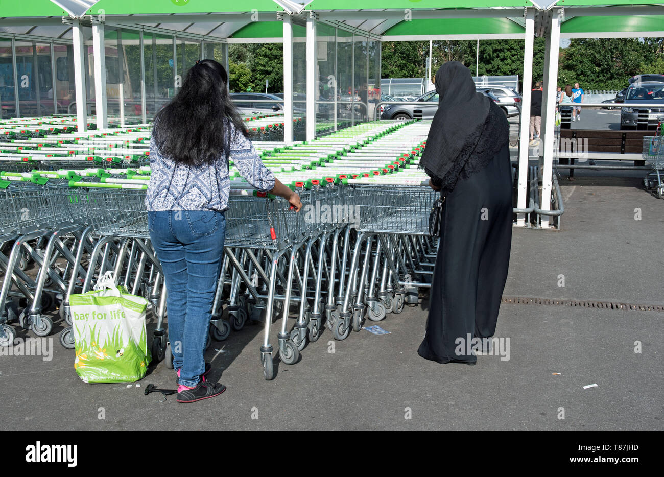 Zwei Damen mit Supermarktwagen, ASDA Crossharbor, London Borough of Tower Hamlets. Stockfoto