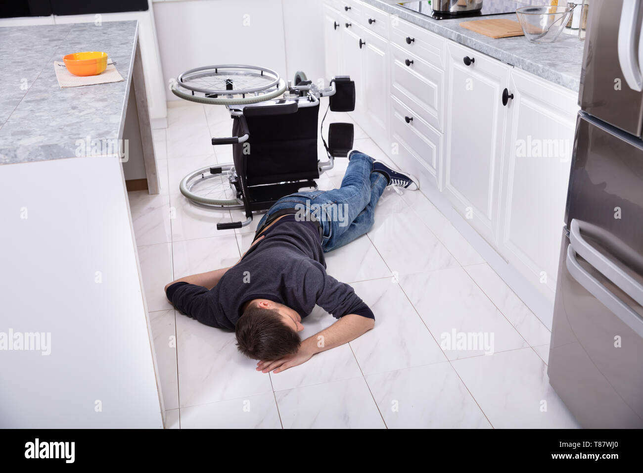 Behinderte Menschen liegen in der Küche nach Gefallen vom Rollstuhl Stockfoto