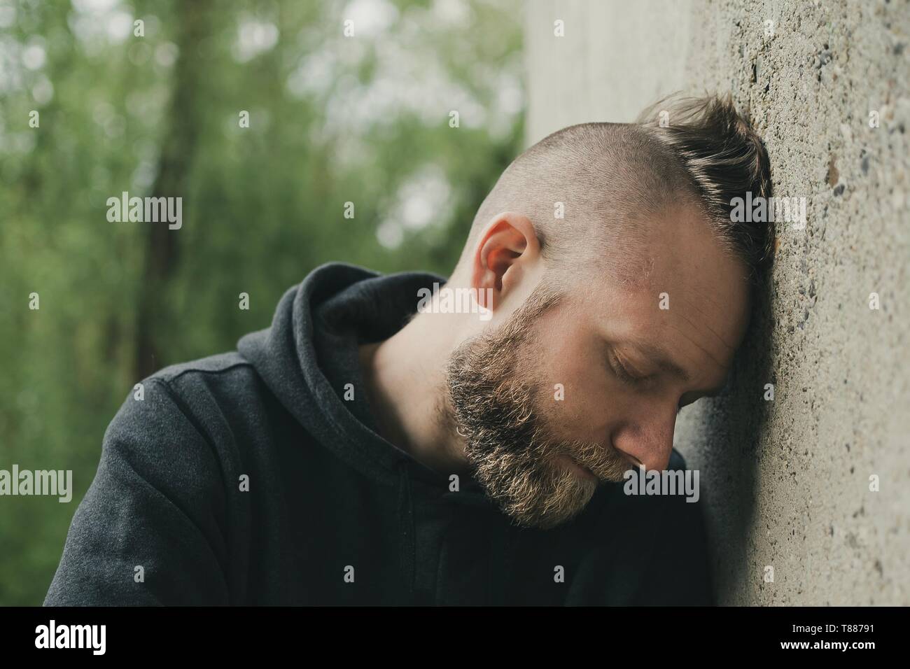Deprimiert und einsamen Mann seinen Kopf gegen eine Wand. Stockfoto