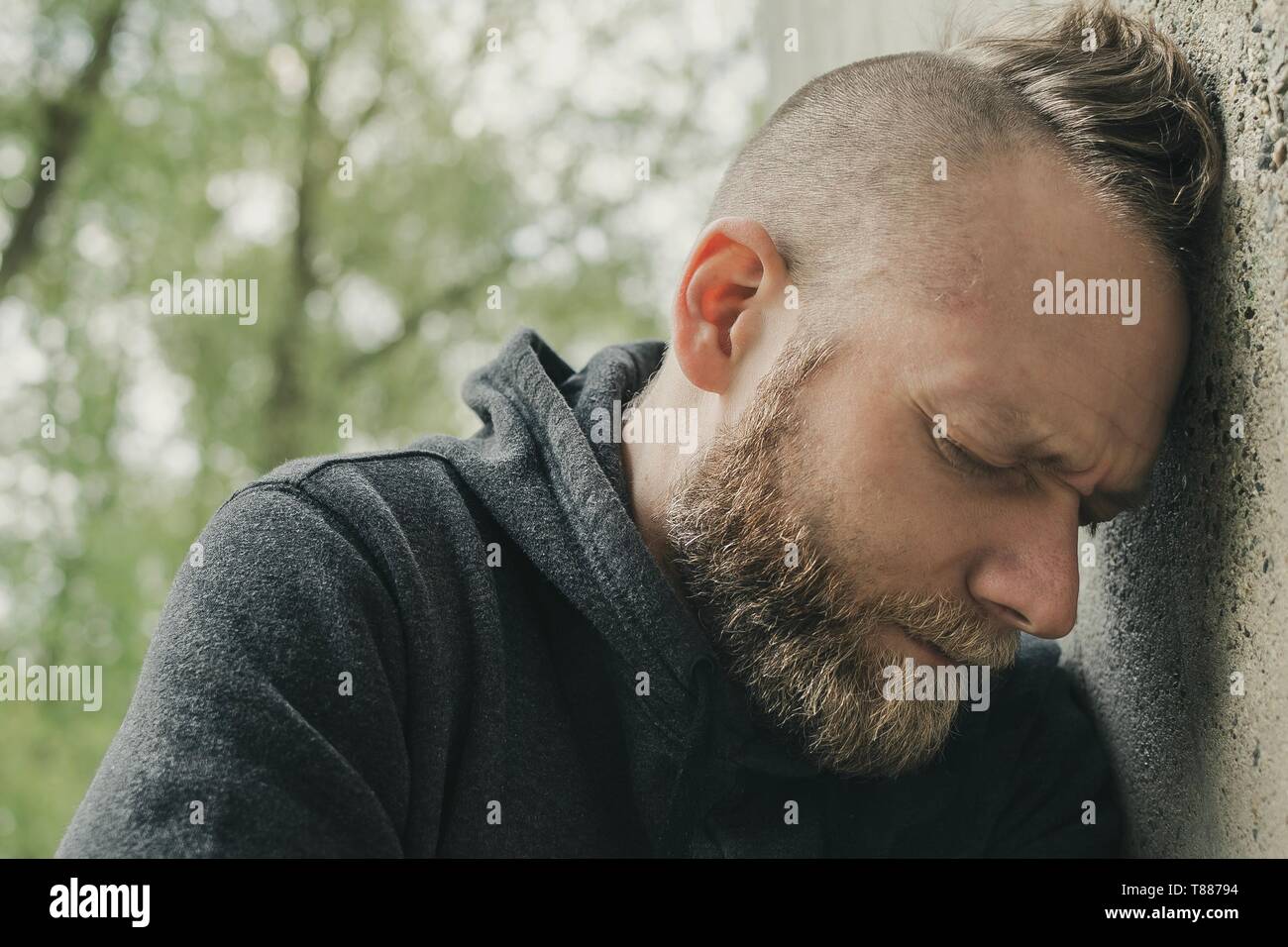 Deprimiert und einsamen Mann seinen Kopf gegen eine Wand. Stockfoto