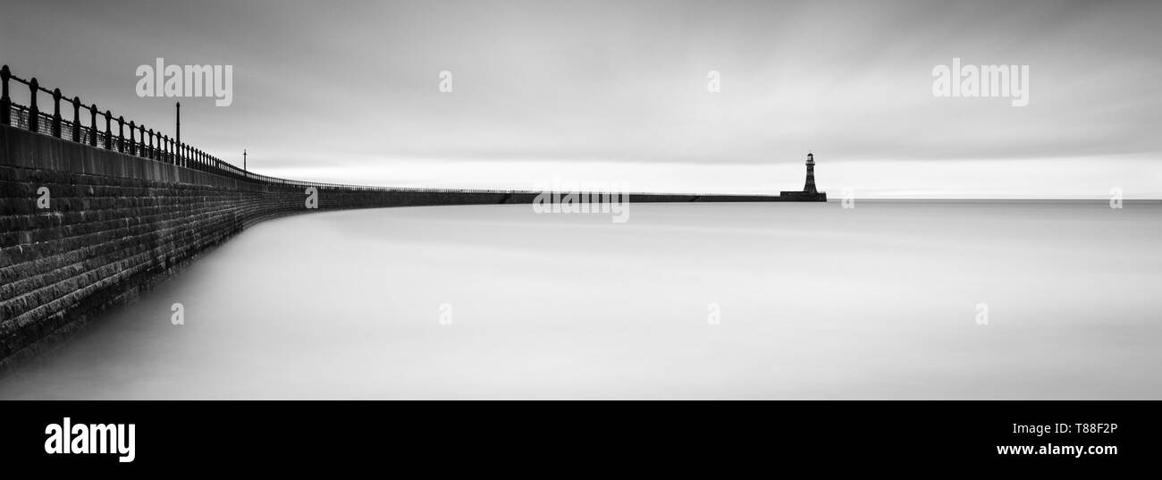Winter Wolken bietet ideale Bedingungen für einen Panoramablick auf die lange Belichtung B&W von Roker Pier mit einigen weichen Reflexionen in der Nordsee. Stockfoto